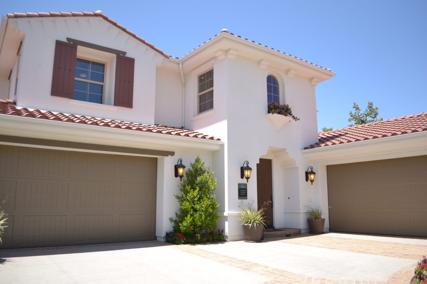 A white house with two garage doors and a driveway.