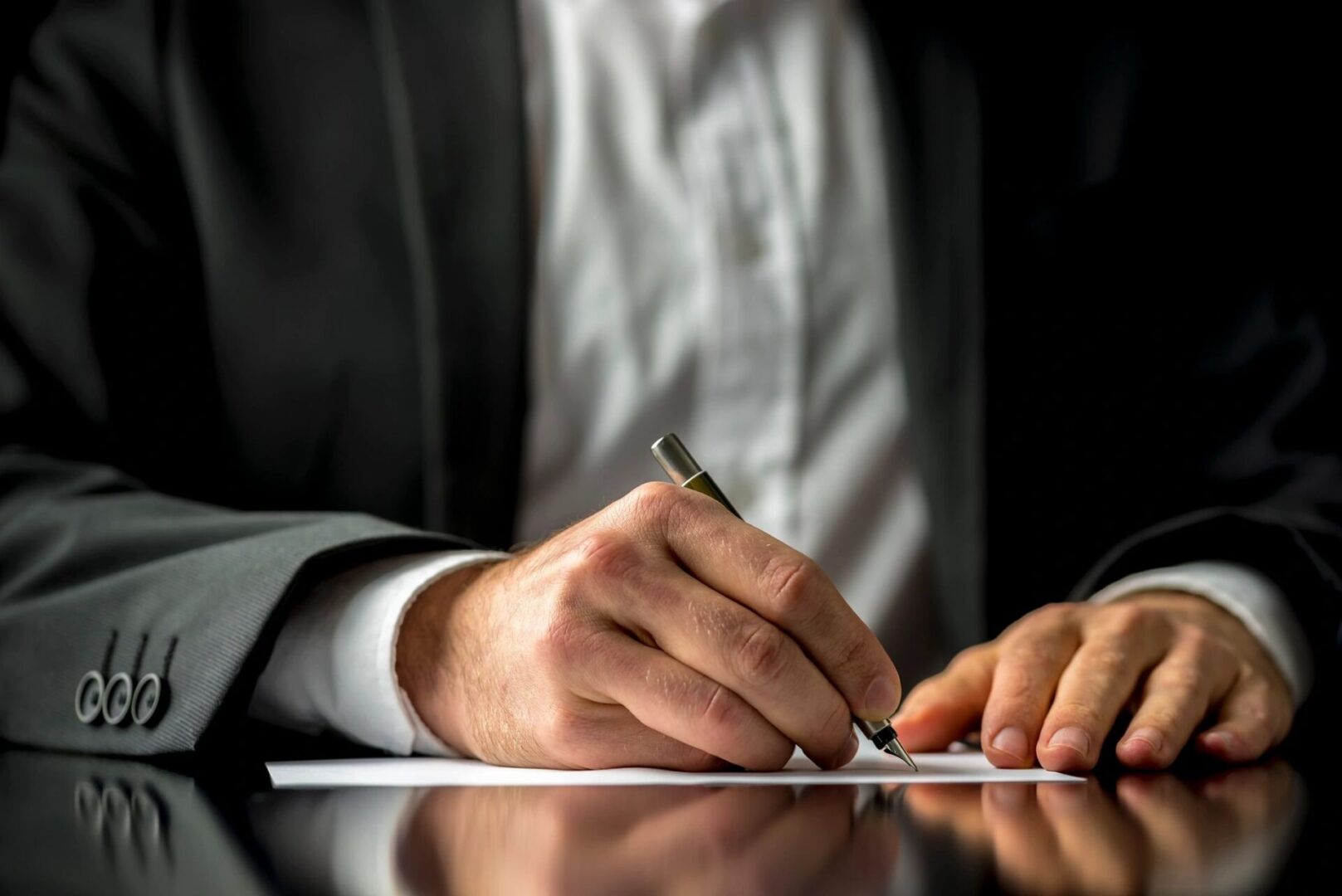 A person writing on paper with pen and ink.