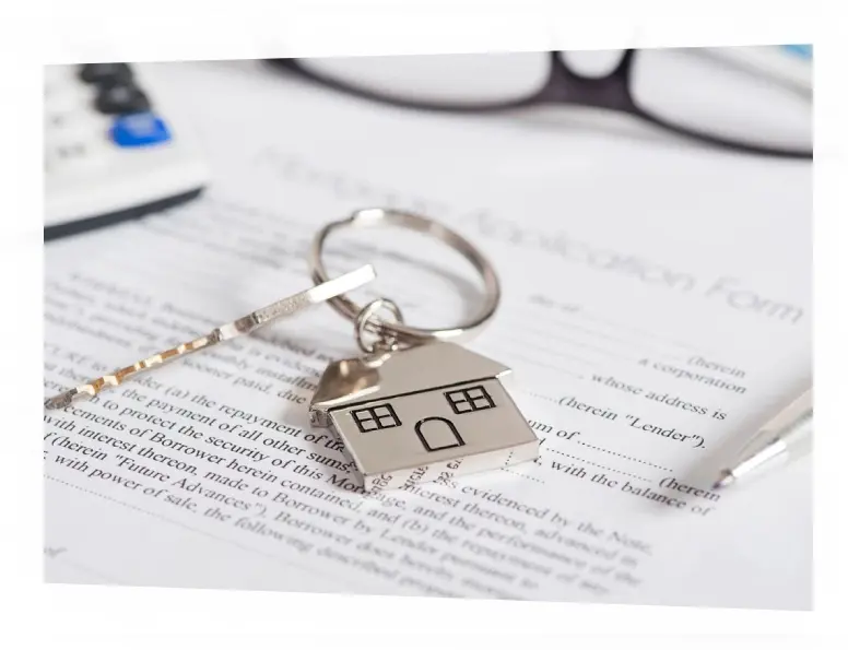 A key chain with a house on it sitting on top of some papers.